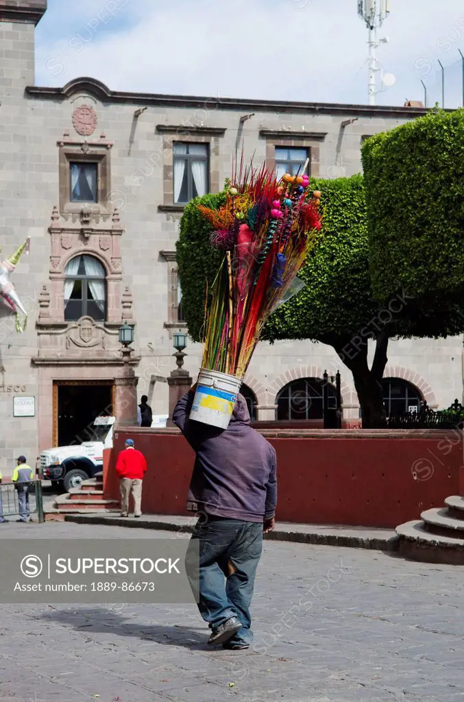 Mexico, Guanajuato, Street Vendor Carrying Bucket Of Flowers; San Miguel De Allende