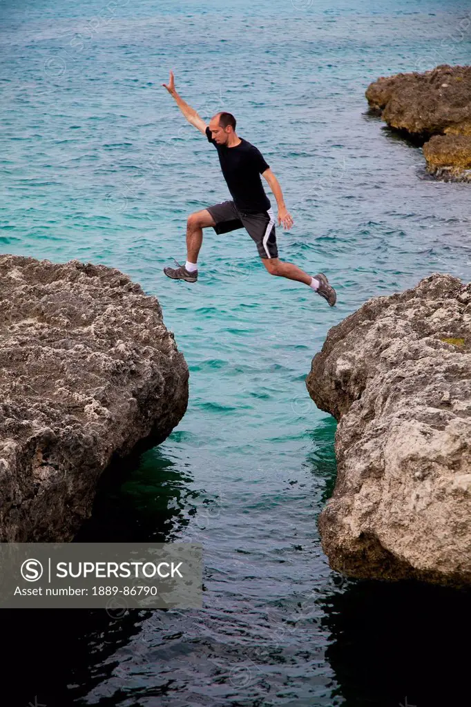 Aruba, Man Jumping Rocks On Tropical Sea; Orangestad