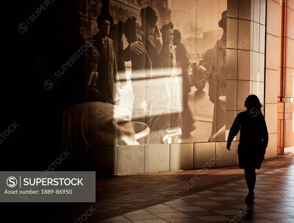 Japan, Woman Walking By Large Picture Displayed On Wall Along Walkway; Tokyo