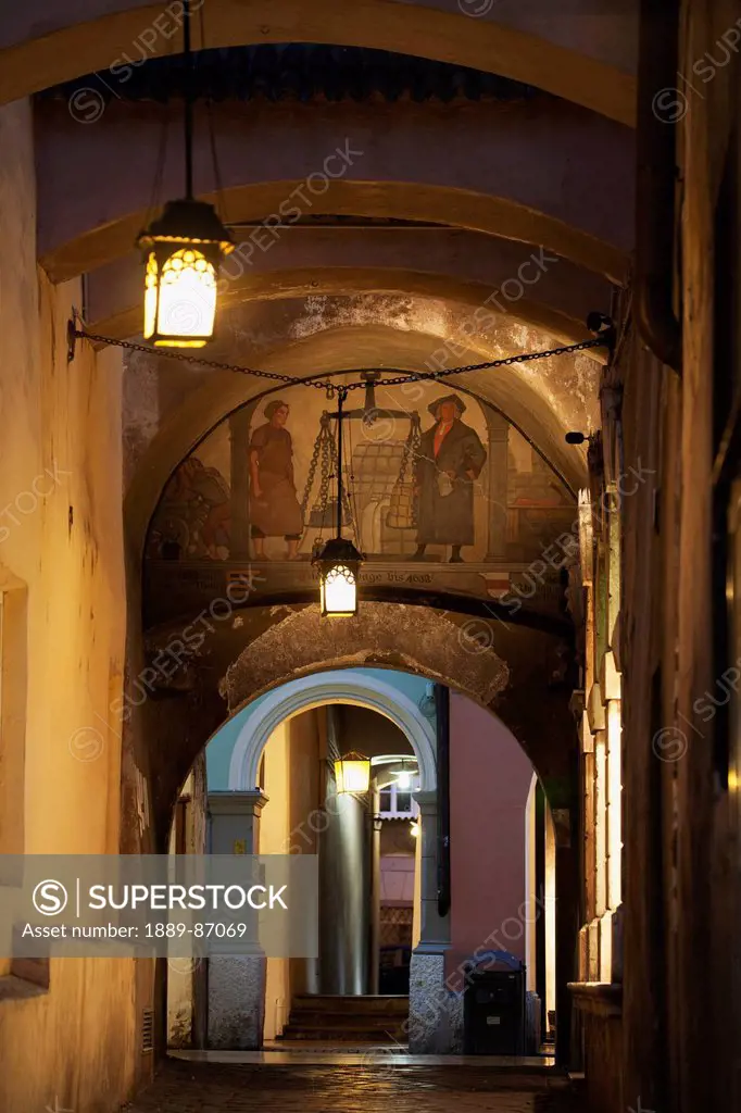 Italy, Alto Adige, Arched Passageway With Fresco And Street Lamps At Night; Bolzano