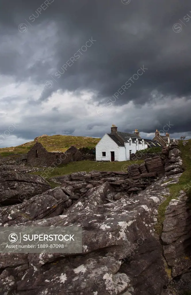 Uk, Scotland, Highlands, Stone Wall And Cottage Houses Under Stormy Sky; Applecross Peninsula