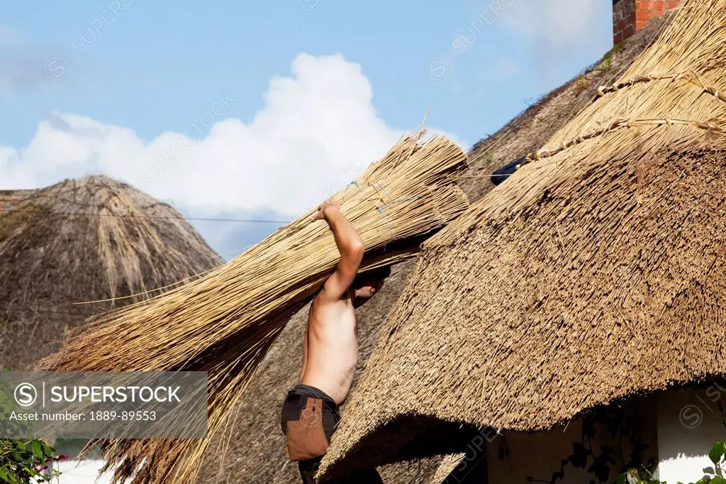 A thatcher working on a thatched roof;Adare county limerick ireland
