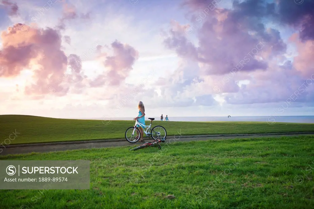 Woman Cycling Through The Coastal Makai Golf Course; Princeville, Kauai, Hawaii