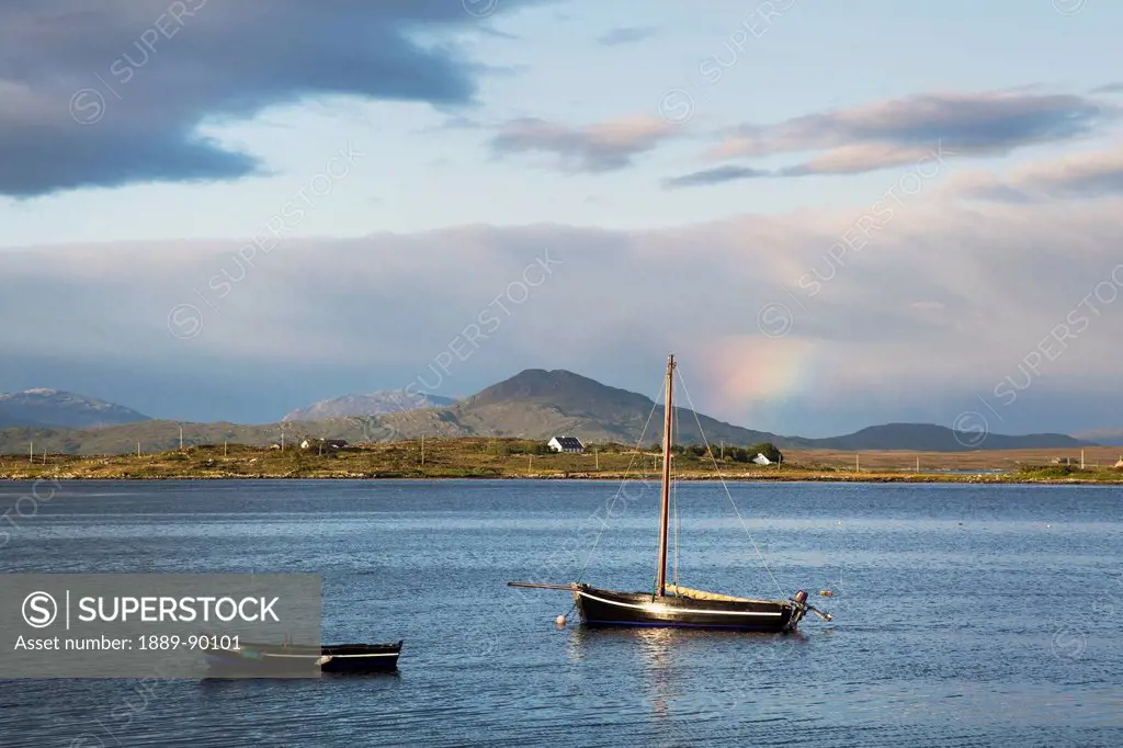 Boats mooring on a lake with clouds and hills in the background near roundstone;County galway ireland