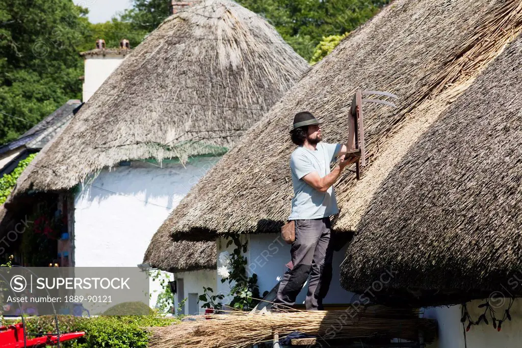 A man repairing a thatched roof on a house;Adare county limerick ireland