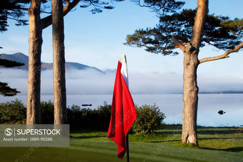 A red flag on a golf course at the water's edge;Killarney county kerry ireland