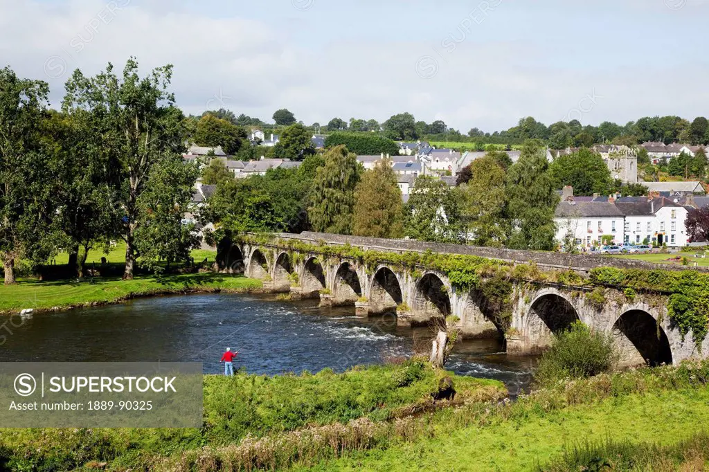 A bridge crossing the river nore with a man fishing at the water's edge;Inistioge county kilkenny ireland