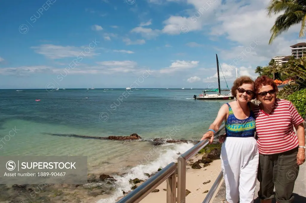 Two sisters posing along the shoreline, Waikiki Beach; Oahu, Hawaii, United States of America