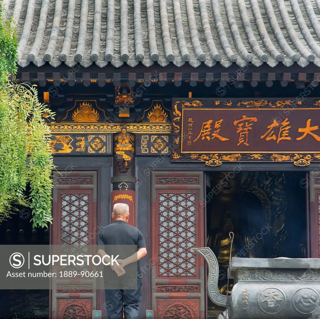 A man stands in front of an ornate wall at the Giant Wild Goose Pagoda; Xi'an, Shaanxi, China
