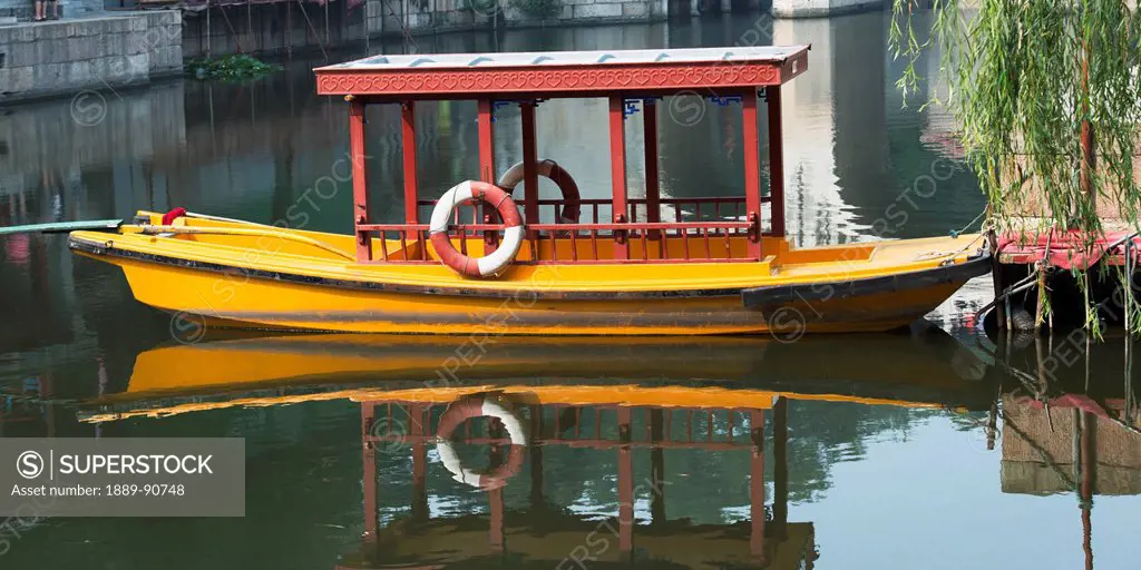 A boat sitting in tranquil water at the shoreline; Beijing, China