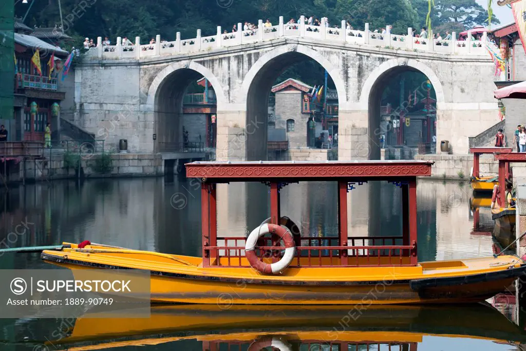 A boat sitting in tranquil water at the shoreline; Beijing, China