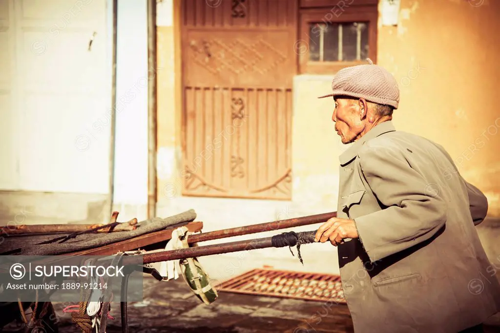 Old man pushes cart; Dali City, Yunnan Province, China