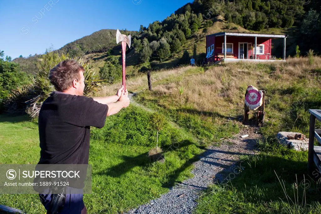 A Man Takes An Attempt At An Axe Throw At Blue Duck Lodge, In Whanganui National Park; Whakahoro, New Zealand