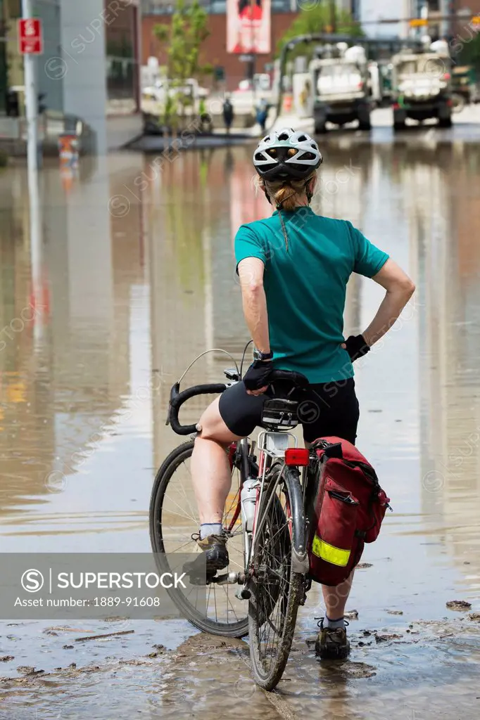 A Woman Sits On Her Bike Looking At The Devastation Of A Flood; Calgary, Alberta, Canada