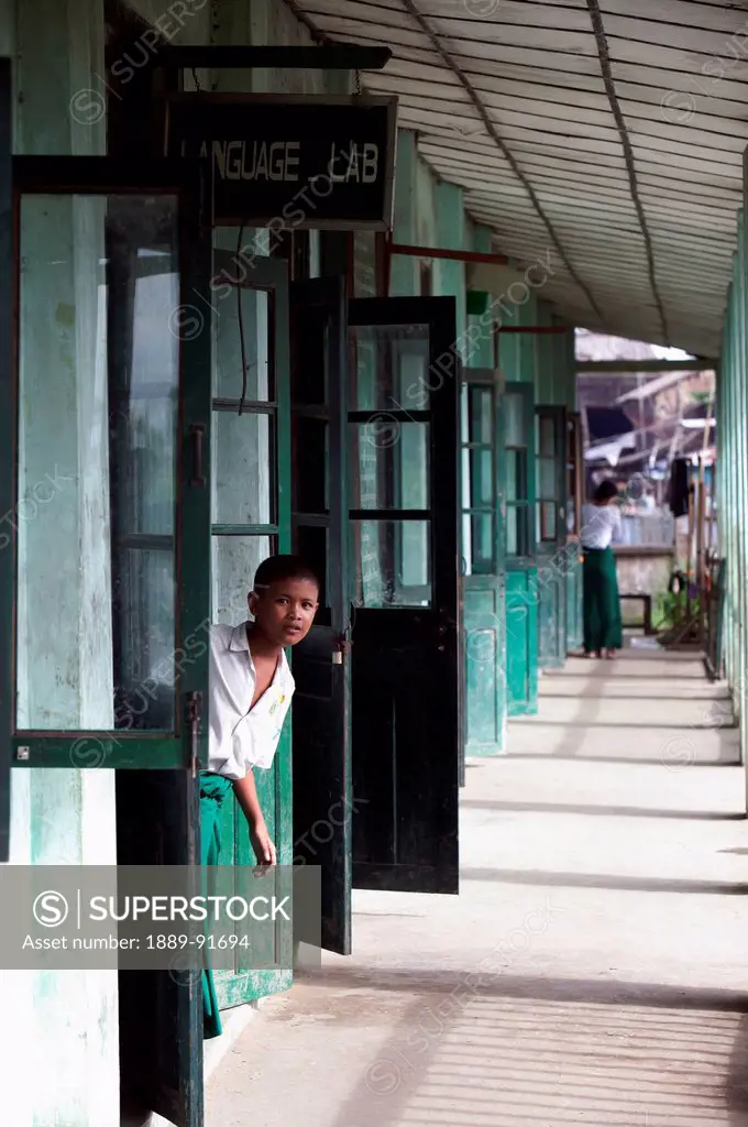 A Student Looks Out Of The Classroom Into A Corridor At School; Labutta, Burma, Myanmar