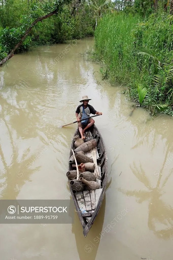 Fisherman Travelling By Boat With Fish Traps, Ayeyarwady River Delta, Myanmar; Ayeyarwady, Burma