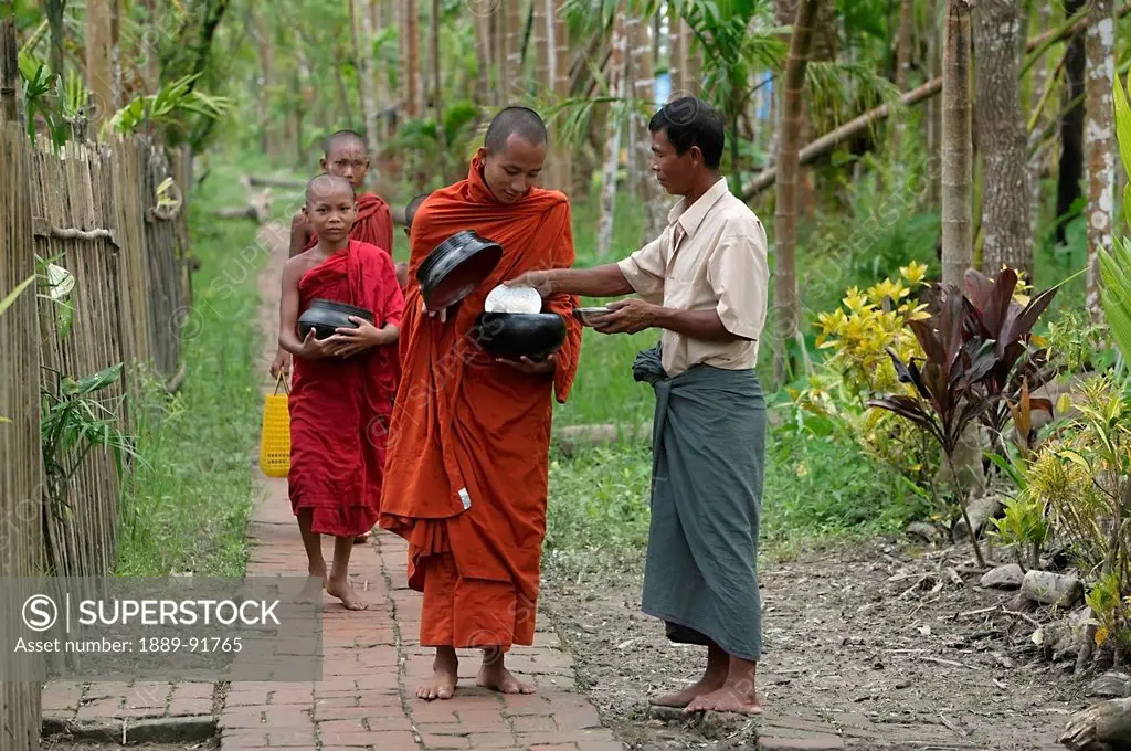 Buddhist Monks Receiving Alms From Villager, Ayeyarwady River Delta, Myanmar; Ayeyarwady, Burma