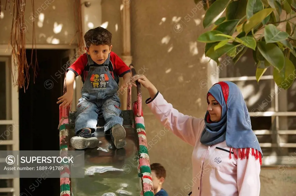 A teacher guides a student down a slide at the Early Childhood Development Union; Alexandria, Egypt