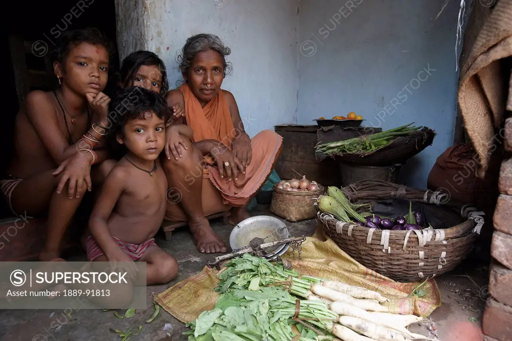 A grandmother with her three grandchildren selling vegetables at the market; Cuttack, Odisha, India