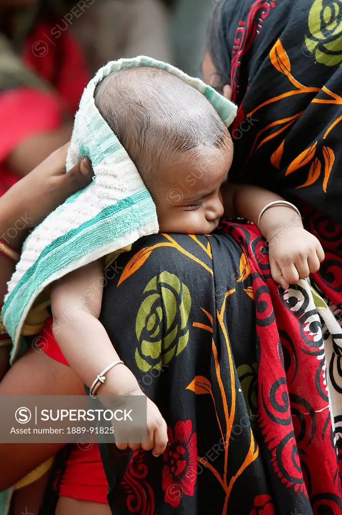 A woman holds her baby on her shoulder; Badabhuin Village, Badamba, India
