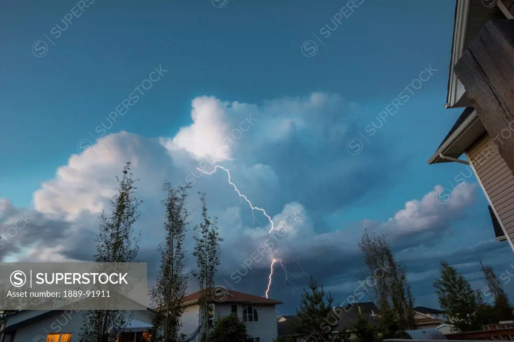 Lightning strikes from a storm cloud over houses; Fort McMurray, Alberta, Canada