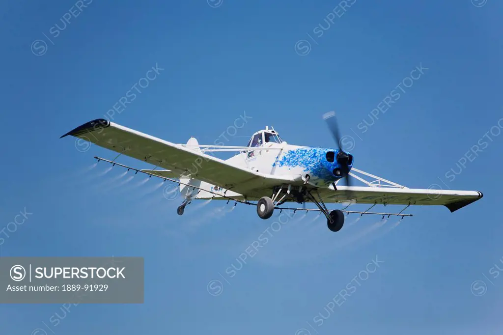 Crop Dusting Plane In A Blue Sky; Crossfield, Alberta, Canada
