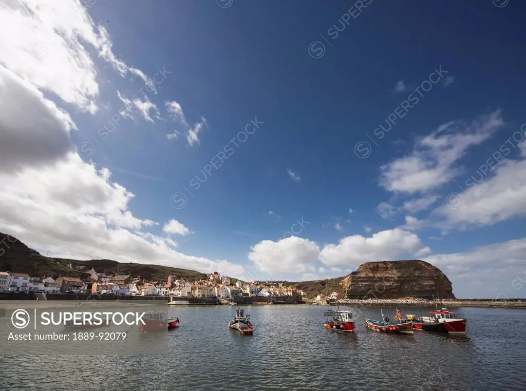 Boats Mooring In A Row In A Harbour With Houses Along The Waterfront; Staithes, Yorkshire, England