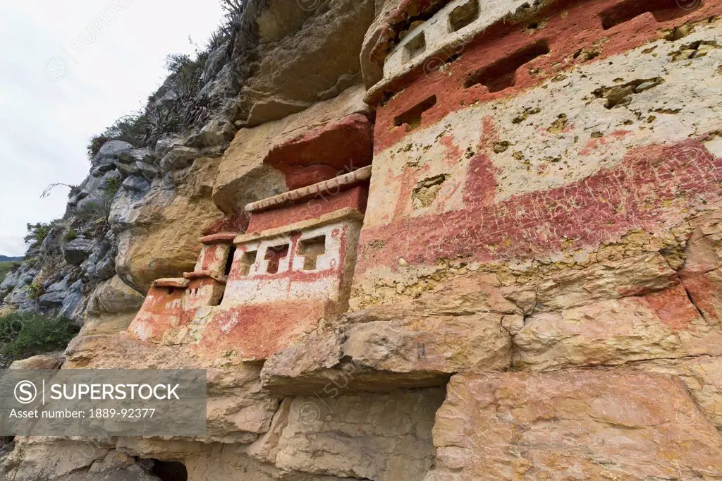 T-shaped windows in the chullpas (stone tomb chambers) of the Chachapoya culture with walls colored with red figures, nestled in the limestone cliffs ...