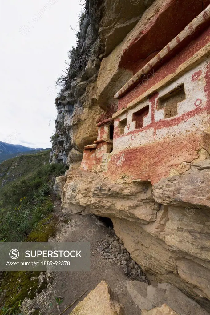T-shaped windows in a chullpa (stone tomb chamber) of the Chachapoya culture with walls colored with red figures, nestled in the limestone cliffs of C...