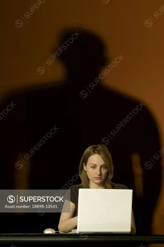 Woman On Computer with Menacing Shadow