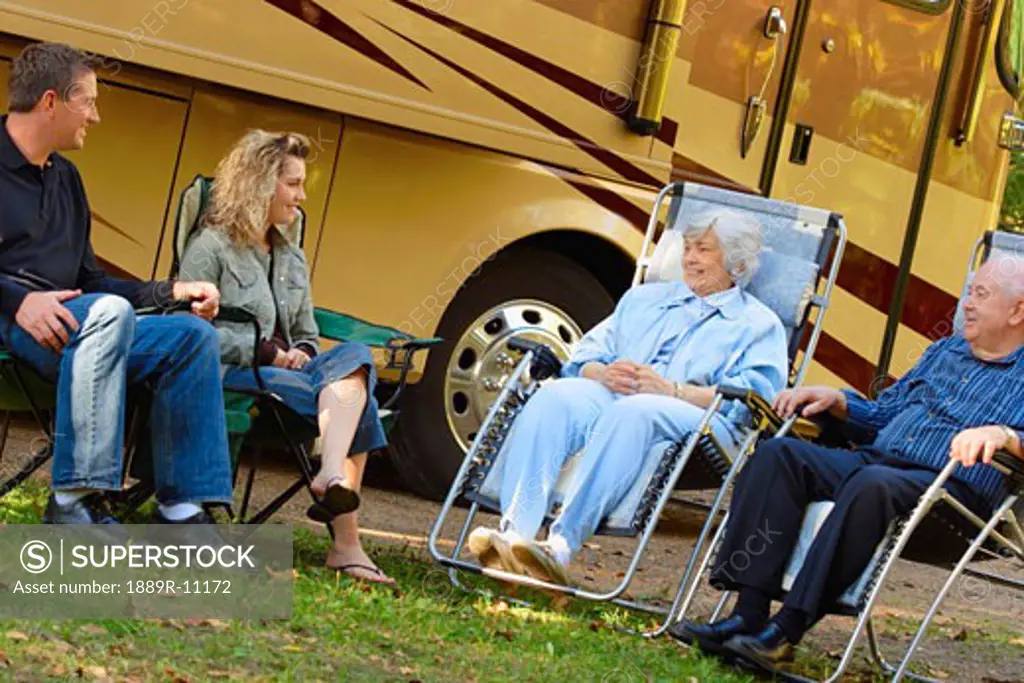 Couples siting on lawn chairs outside motor home