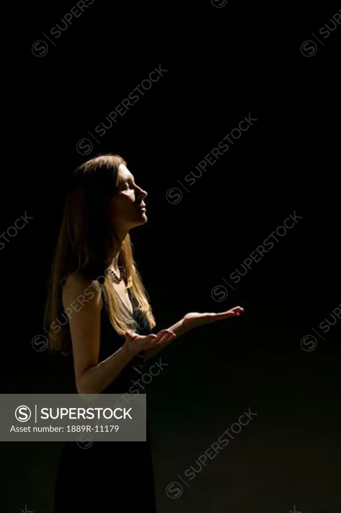 Woman's profile with hands raised and eyes closed