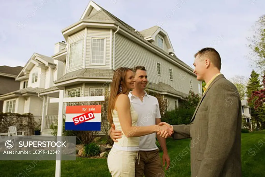 A couple shaking hands with a realtor