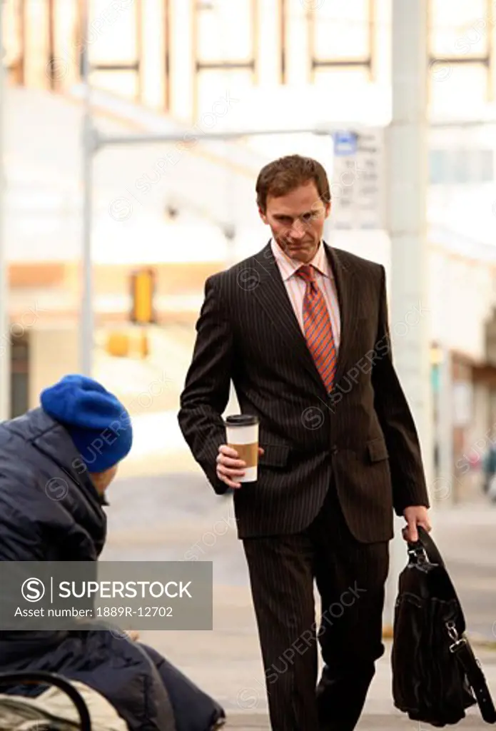 Businessman walking by homeless man
