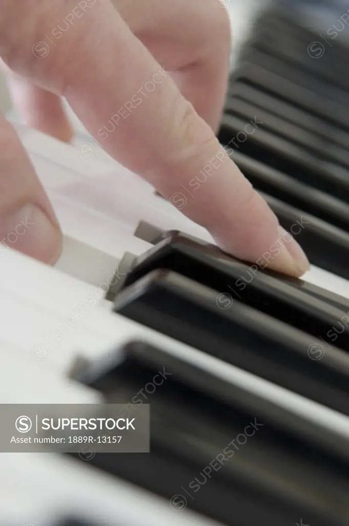 Close up of finger playing piano keyboard