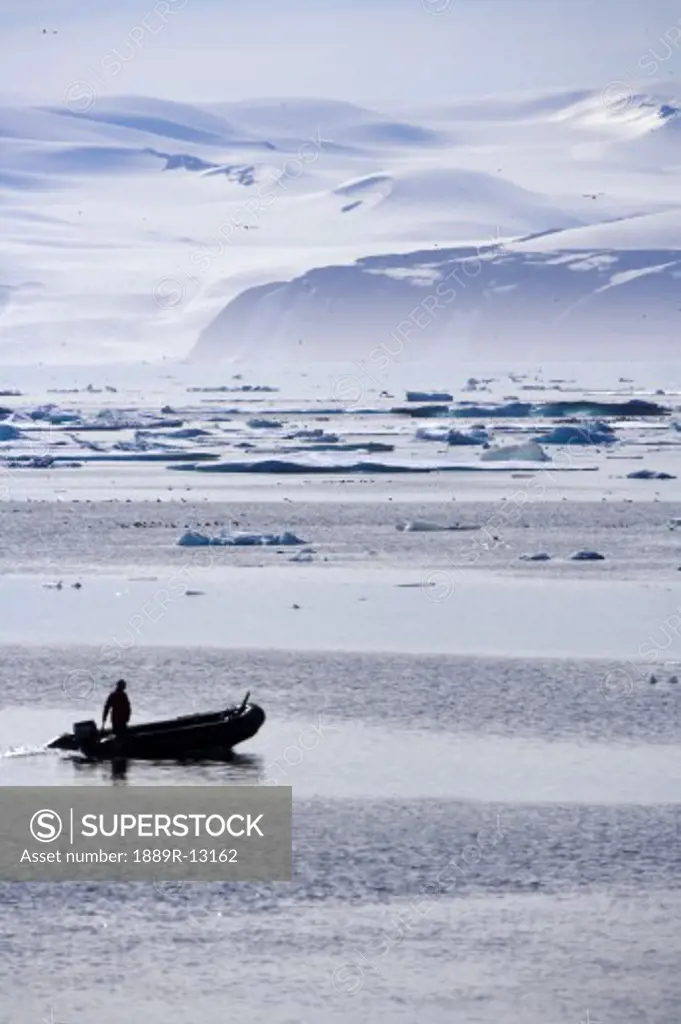 Person in boat by ice berg off coast of Nunavut, Canada