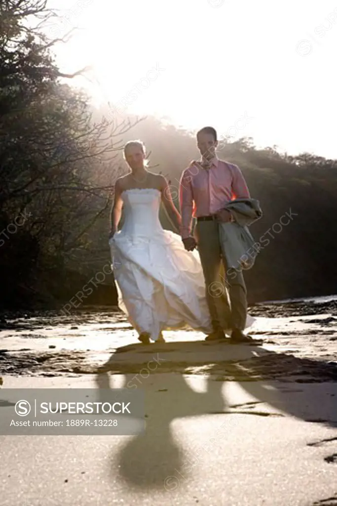 Bride and groom holding hands on beach