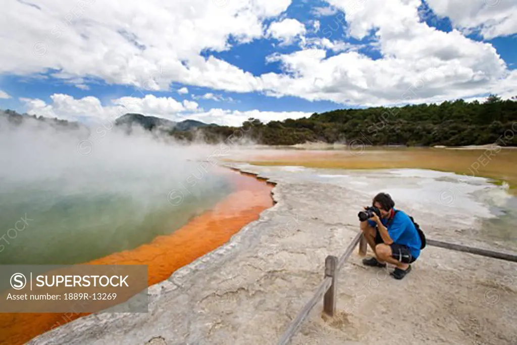 Man at Champagne Pool at geothermal site, Wai-O-Tapu Thermal Wonderland on North Island of New Zealand