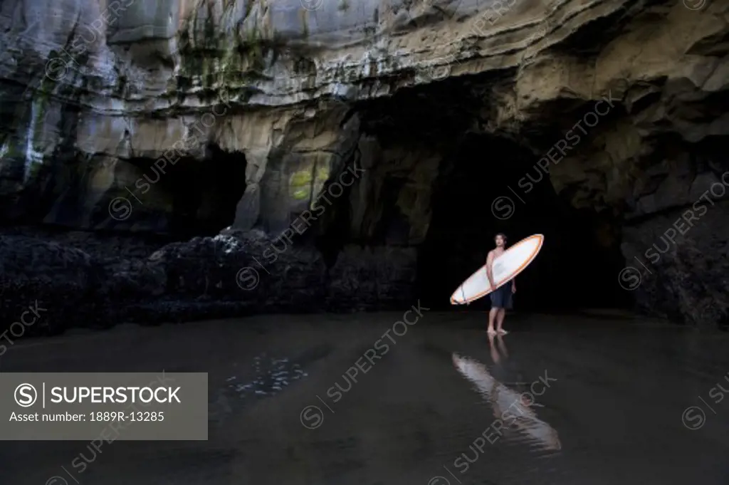 Surfer inside a cave at Muriwai, New Zealand