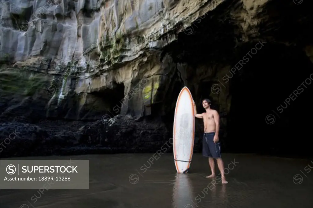 Surfer inside a cave at Muriwai, New Zealand