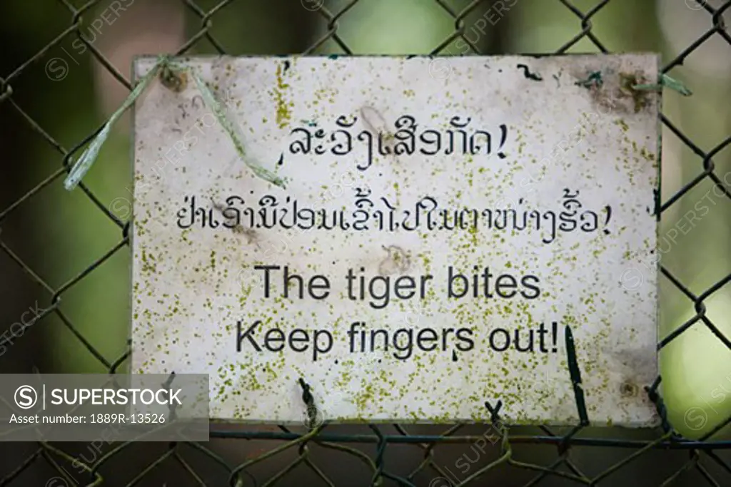 A sign for a tiger biting on a fence in Laos, Thailand