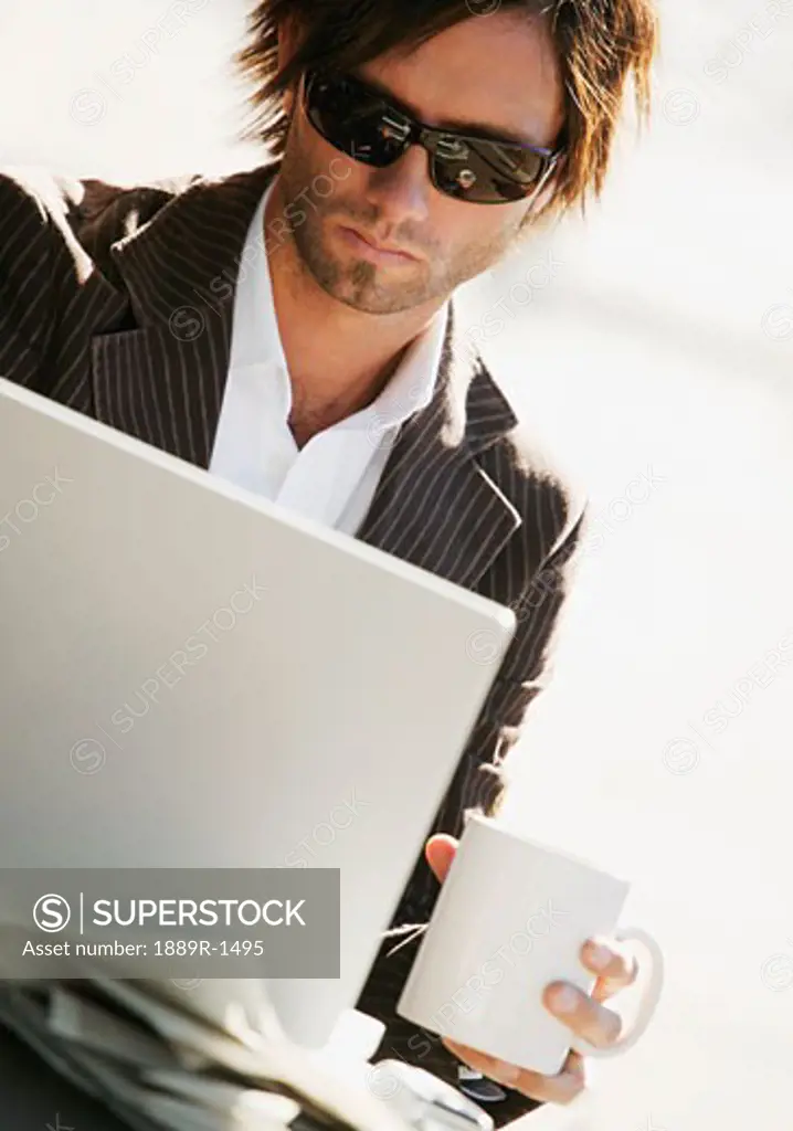 Man working on computer holding coffee