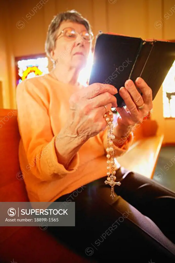 Woman holding rosary beads and bible