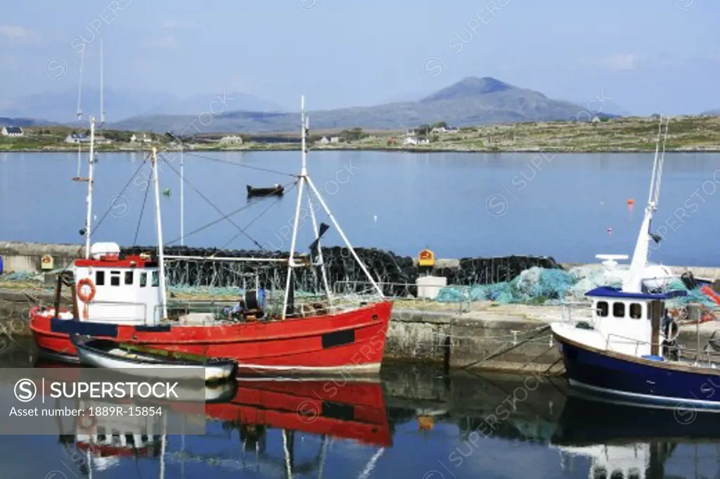 Roundstone, Co Galway, Ireland; Boats in the harbour with Inishnee Island and Cashel Mountain in the background