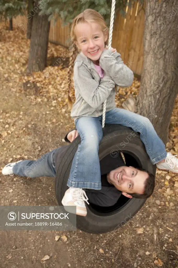 Father and daughter on tire swing