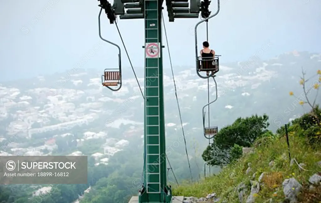 Capri, Italy; Woman riding chairlift to the top of Monte Solaro