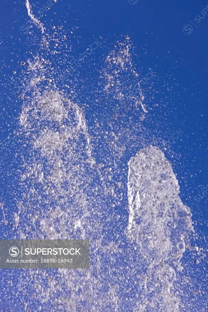 Water spouting into air against blue sky  
