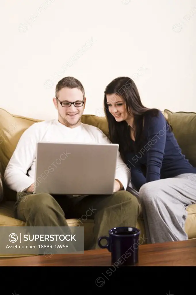Couple; Couple sitting on couch, looking at a laptop togeter
