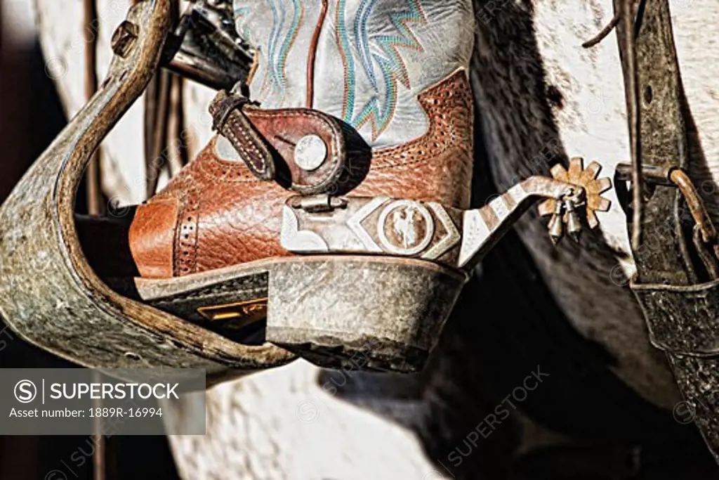 Cowboy boot heel and spur in saddle stirrup  