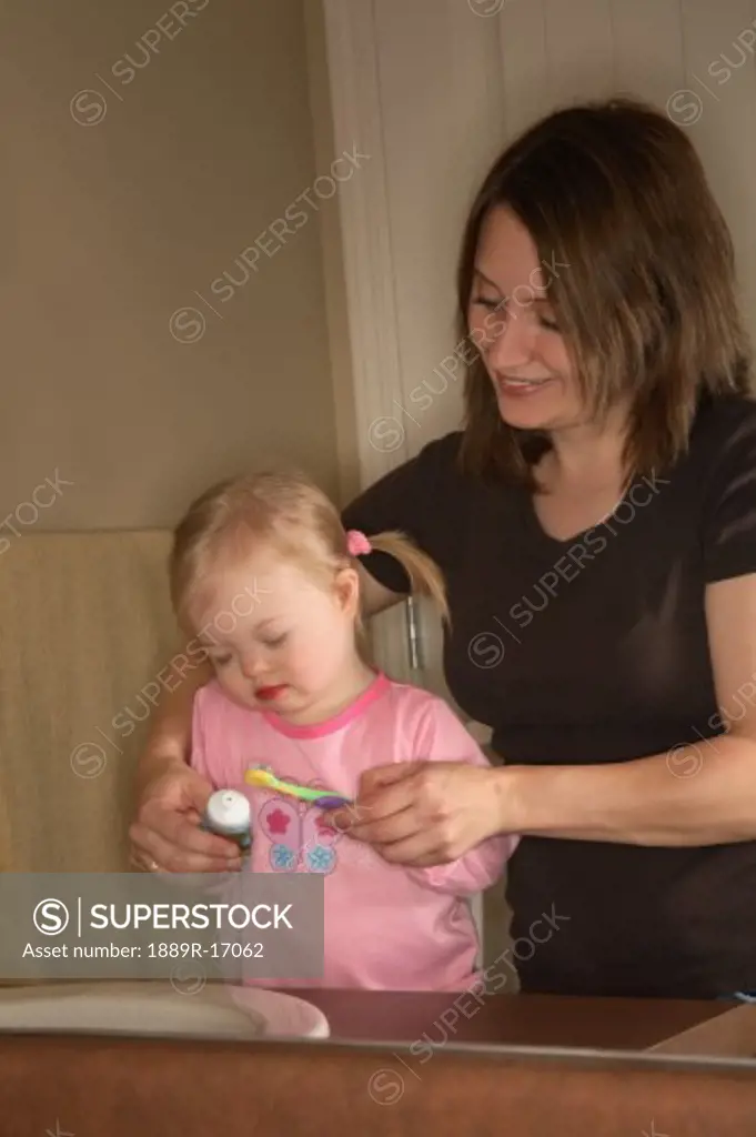 Woman and girl; Mother brushing daughter's teeth
